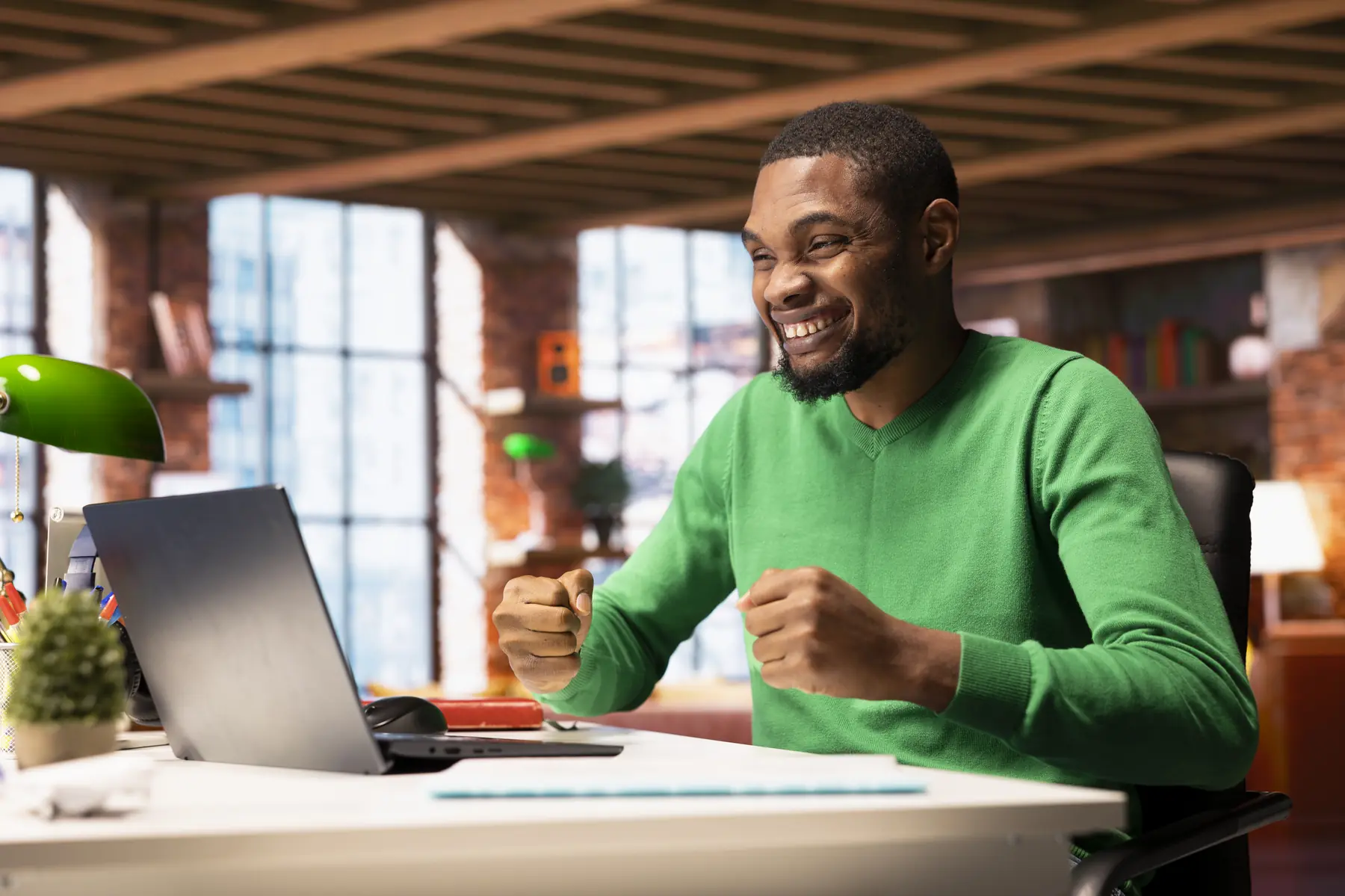 A man celebrating at his laptop