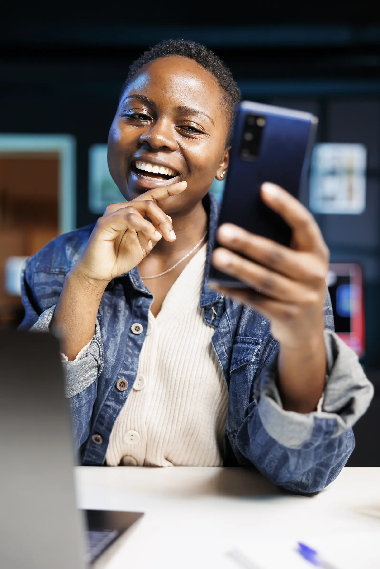 A young woman smiling as she shares something on her phone